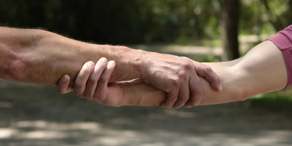 Podanie pomocnej ręki przez terapeutę dla pacjenta symbolizujące wspracie